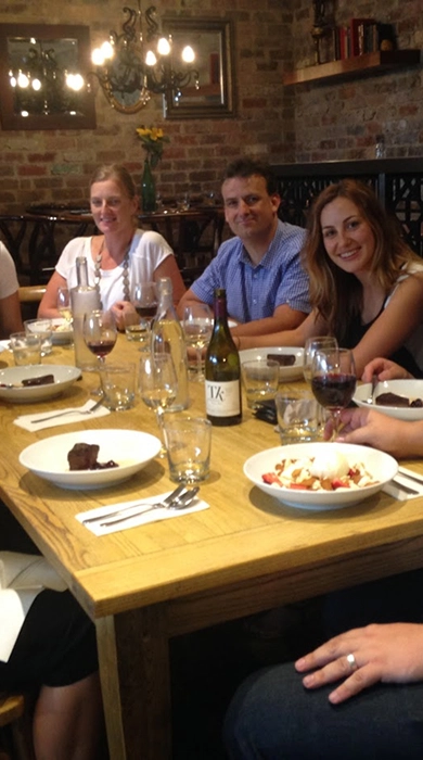 A group of colleagues enjoying a dinner at a restaurant with rustic brick walls and warm lighting, reflecting the Quattro Architecture culture.