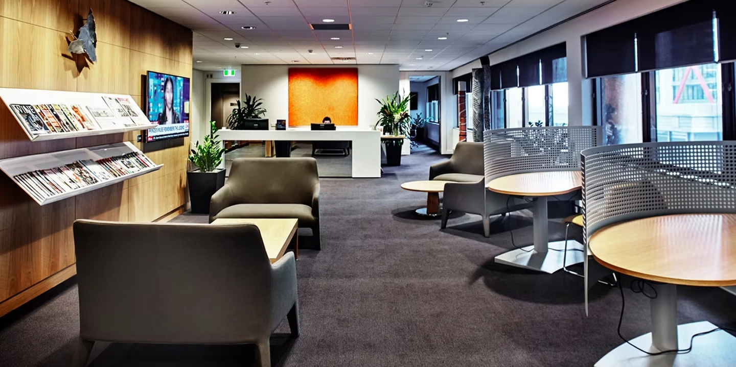 Modern office interior with wood paneled walls, lounge seating, and circular desks, showcasing the professional workspace of Quattro Architecture.