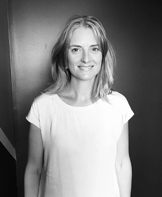 A professional architect from the Quattro Architecture team posing for a portrait in a modern, minimalist office setting with a dark background.